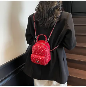 Detail of red quilted leather mini backpack with rhinestones and chain strap worn by a model