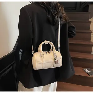 Borsa bowling chic bianco crema in pelle martellata indossata da una modella sulle scale