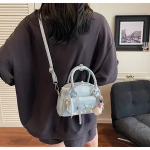Détail d'un mini sac bowling bleu clair avec dentelle et nœud porté par un mannequin