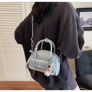 Détail du sac à main bleu clair avec nœud, bordure en dentelle et breloques en perles