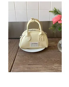 Dettaglio di una borsa bowling giallo crema con etichetta decorativa in tessuto