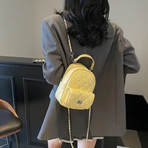 Yellow quilted mini backpack with sparkling crystals and chain strap on grey blazer