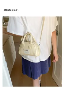 Modèle porte le sac bowling crème en bandoulière pour montrer la taille et la sangle