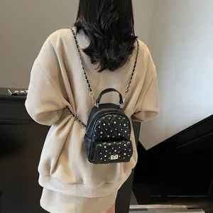 Black quilted mini backpack with pearl accents and silver chain straps on model