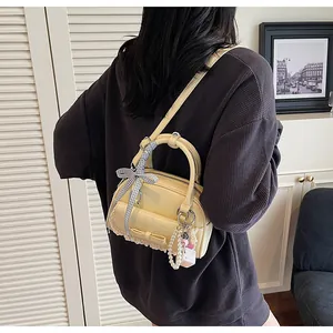 Détail du mini sac à main jaune clair avec nœud à carreaux bleus et dentelle