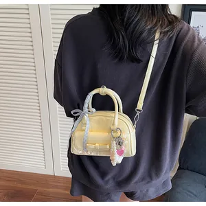 Détail du sac à main jaune clair avec nœuds, bordure en dentelle et breloque perle