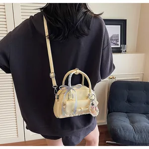 Détail du sac bowling en cuir verni jaune clair avec nœud et breloque perle