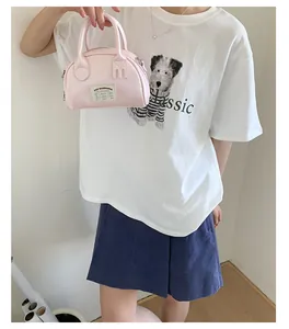 Dettaglio della mini borsa bowling rosa chiaro con doppi manici ed etichetta in tessuto