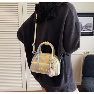 Détail du sac bowling en cuir verni crème avec nœud bleu et charms en perles élégants
