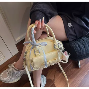 Détail du sac en cuir verni jaune pâle avec nœuds en ruban et breloques perles