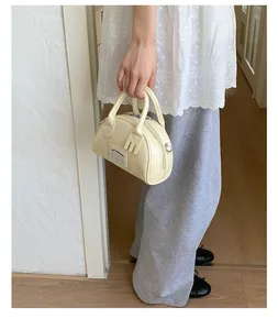Vue détaillée du mini sac bowling crème avec étiquette en tissu et fermeture éclair