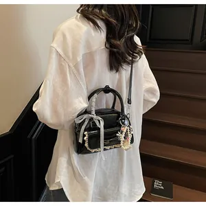 Détail du sac à main noir brillant avec nœud et perles sur un escalier vintage