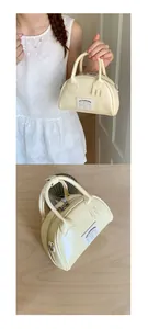 Vue détaillée du mini sac bowling crème montrant la couture et l'étiquette tissée