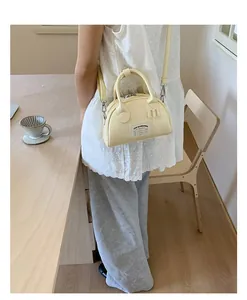 Détail du sac Boston crème avec poignées en cuir et étiquette textile dans un café
