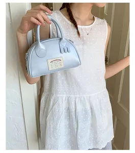 Détail du mini sac bowling bleu clair avec étiquette rétro et breloque en forme de fourchette