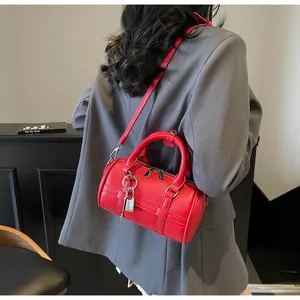 Dettaglio borsa Boston in pelle martellata rossa con lucchetto argento e tracolla