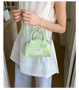 Détail du mini sac bowling vert clair avec écusson rétro et bandoulière amovible