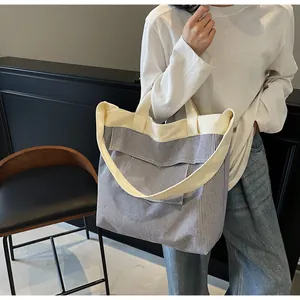Dettaglio di una borsa tote in tela a righe con manici a contrasto e tasca con patta