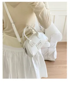 Détail du sac bandoulière en similicuir blanc en forme de demi-lune avec étiquette vintage