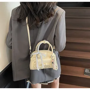 Détail du sac bowling en cuir crème avec dentelle, nœud et décoration de perles nacrées