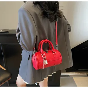 Dettaglio borsa Boston in pelle martellata rossa con lucchetto d'argento e manici