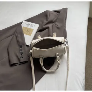 Dettaglio borsa bowling crema con trama litchi su un blazer grigio elegante