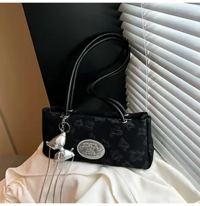 Detail of black jacquard underarm bag with silver oval logo and bow pendant