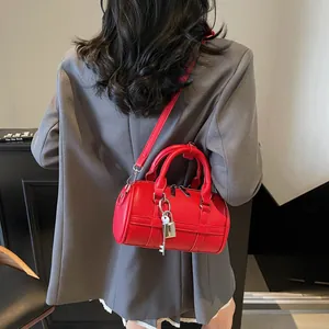 Borsa bowling rossa in pelle grana con lucchetto indossata su blazer grigio
