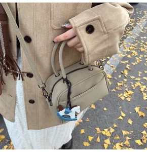 Outdoor shot of khaki retro crossbody pillow bag with wooden rocking horse pendant