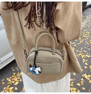 Detail of beige Boston bag with horse pendant on an autumn street setting