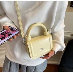 Detailweergave van een beige minimalistische kleine vierkante handtas gedragen als tas