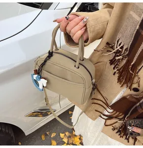 Detail of mini Boston bag in beige PU leather with a blue horse charm and shoulder strap