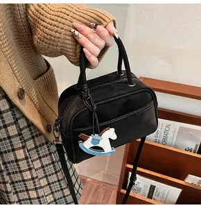 Detail of a vintage black suede Boston bag featuring a playful rocking horse charm