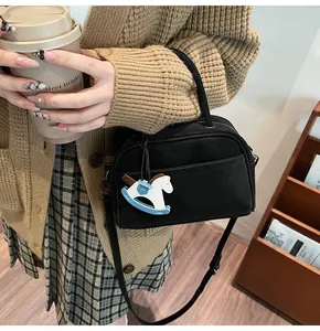 Detail of black matte leather shell-shaped crossbody bag with wooden horse charm