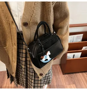 Detail of black crossbody pillow bag with suede texture and white horse charm