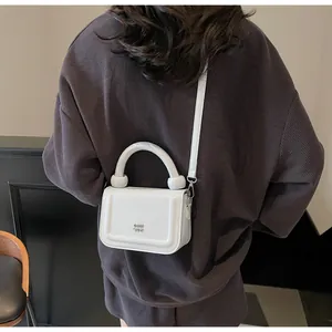 Elegante witte glanzende handtas met gebogen handvat gedragen door een model