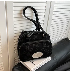 Détail du tissu jacquard floral noir et de la bandoulière en cuir d'un sac à bandoulière
