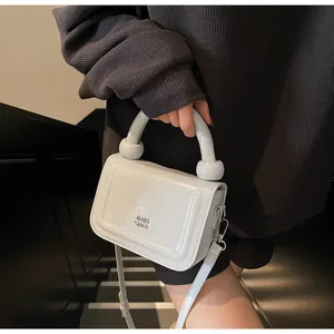 Glanzende witte tas met rond handvat en afneembare riem, vastgehouden door een model