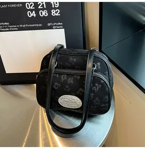 Détail du sac bandoulière noir avec broderie papillon 3D et plaque logo argentée