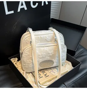 Détail du sac carré ivoire à motif floral embossé avec logo en métal et fermeture