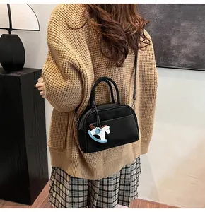 Detail of a chic black Boston bag with a cute rocking horse charm and metal zipper
