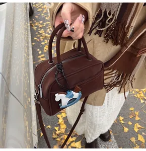 Close-up of brown retro mini boston bag with blue rocking horse charm in ginkgo setting