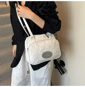 Détail du petit sac blanc gaufré avec plaque de marque argentée et bandoulières