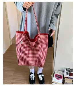 Detail of red checkered canvas tote bag with red shoulder straps and classic red lining