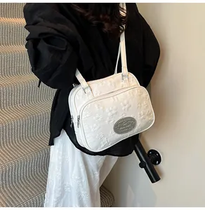 Vue détaillée de la texture jacquard florale 3D et de la plaque logo argentée du sac