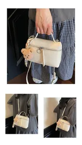Detail of white box bag with cracked texture, round zip pull and brown bear charm