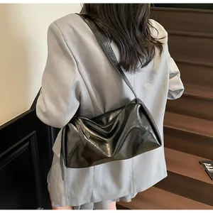 Minimalistische schwarze Schultertasche aus glänzendem Leder an einem Model gezeigt