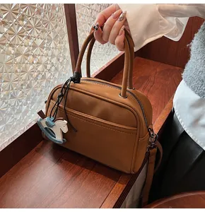 Detailed view of a brown vintage bowling handbag with a blue horse charm on a wood table