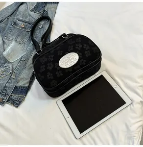 Détail du petit sac carré noir avec relief floral et plaque logo argentée élégante