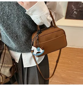 Detail view of caramel brown vintage leather boston bag with a horse charm accessory
